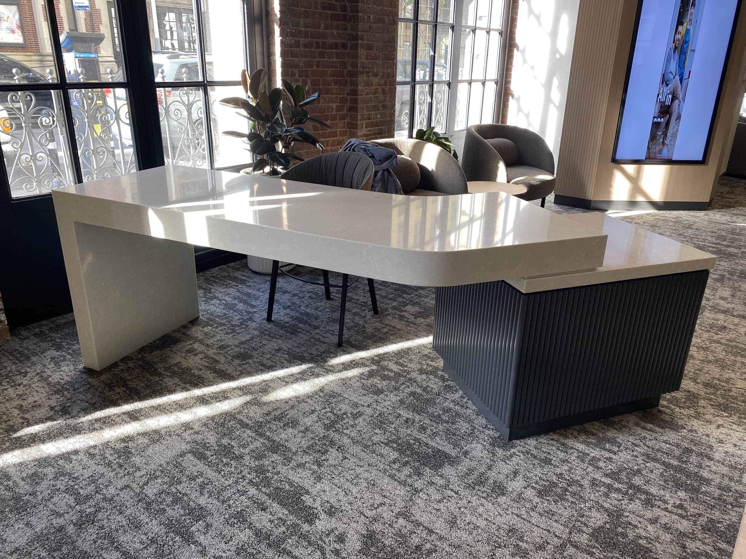 Finished commercial lounge with stone waterfall console and custom millwork by Deerfield Interiors — tri-state area