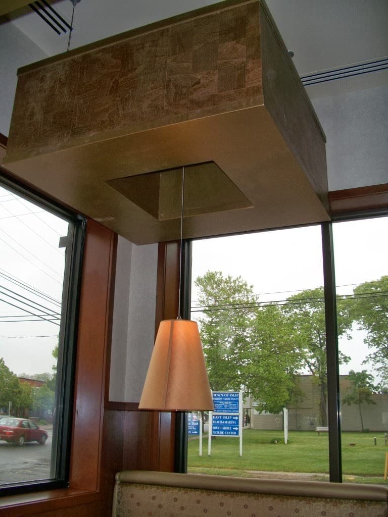 Custom wood-veneer ceiling soffit and window millwork over banquette seating, built by Deerfield Interiors, New York City