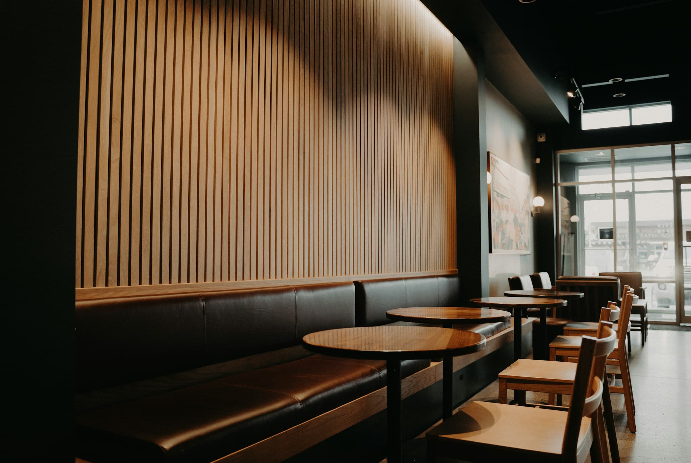 Finished restaurant interior with walnut slat feature wall and leather banquette seating